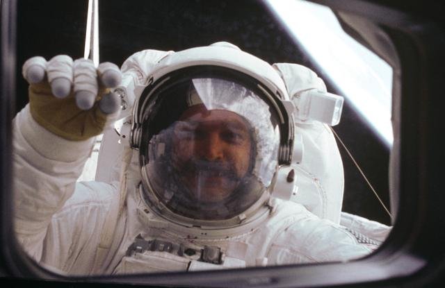 Astronaut S. David Griggs waves to Orbiter during EVA