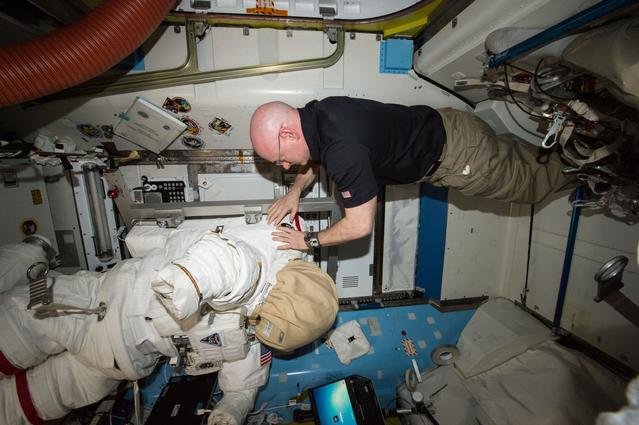 NASA astronaut Scott Kelly relocates spacewalk hardware and suits inside the Quest airlock