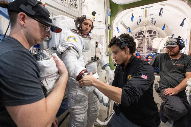 Astronaut Jessica Watkins assists astronaut Josh Kutryk as he practices suiting up in a spacesuit